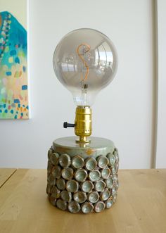 a light bulb sitting on top of a wooden table next to a painting and lamp