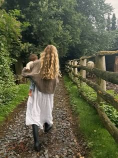 a woman walking down a path carrying a child