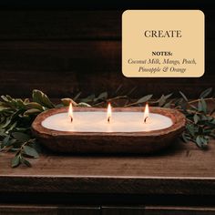 three lit candles sitting on top of a wooden table next to greenery and a sign that says create notes