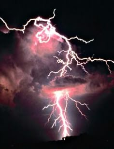 lightning strikes through the dark clouds in the night sky over a mountain range, with bright pink and purple lighting