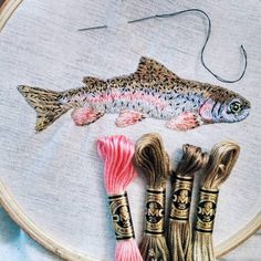 three different types of thread on a piece of fabric with a fish in the background