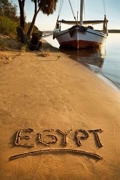 the word egypt written in sand next to a boat on the water's edge