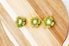 three kiwi slices cut in half on a cutting board