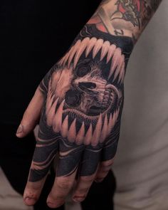 a man with a tattoo on his hand and wrist is wearing a black and grey bear glove