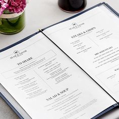 a menu sitting on top of a table next to a vase with flowers in it