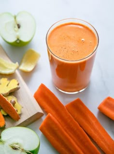 carrots, apples, and apple slices on a table with a glass of orange juice