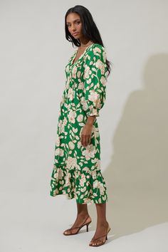 A season favorite list has to include the Lucena Floral Lemy Poplin Midi Dress. It features long sleeves, smocked bodice, and a v-neckline. The bottom has a ruffle hem tier. Wear it with matching ivory heels to create a full look. - Smocked- Deep V-neck- Floral- Lined- Color: Green MultiSize + Fit - Model is 5'10" and wearing size XS- Measurements taken from size S - Chest: 15 1/4"- Length: 49 3/4" Fabric Self: 100% Cotton, Lining: 97% Polyester 3% Spandex Style Number STD14589P Spring V-neck Dress With Smocked Cuffs, Green Ruched Midi Dress For Fall, Green Dresses With Elastic Sleeves For Fall, Green Fall Dress With Elastic Sleeves, Green Dress With Elastic Sleeves For Fall, Green Spring Dress With Elastic Sleeves, Spring Green Dress With Elastic Sleeves, Spring V-neck Smocked Dress For Daywear, Green Long Sleeve Dress With Gathered Sleeves