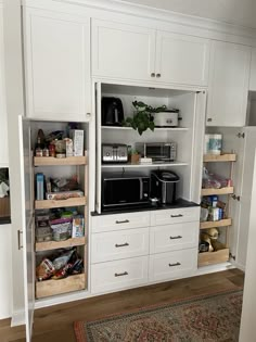 a kitchen with white cabinets and drawers filled with food, drinks and condiments