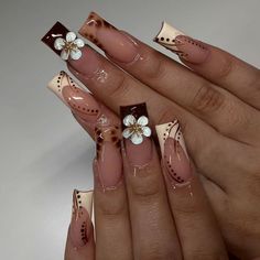 a woman's nails with flowers on them and some brown nail polishes in the foreground