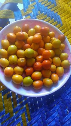 a white bowl filled with lots of fruit on top of a blue tablecloth covered table