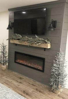 a living room with a fireplace and tv mounted on the wall, decorated for christmas