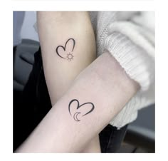 two people with matching tattoos on their arms, one is holding the other's arm