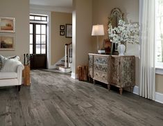 a living room with wood flooring and white furniture in the corner, along with pictures on the wall