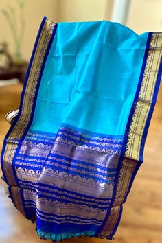 This regal korvai silk cotton saree in rama blue with ink blue border and pallu is handwoven. The saree borders are adorned with traditional motifs in gold zari. The ink blue pallu is grand with a rich gold zari work. Approximate Length 6.5 mtrs (inclusive of blouse length) Approximate weight - 1.2 lbs Approximate Height - 48 - 50" Saree comes with fall, picot and tassels done when applicable. Blouse piece is cut. Kindly Note : The colors you see on your device may vary due to the color reproduction, brightness and resolution of individual devices. If you'd like more clarity before your purchase, please contact our support team. Blue Slub Silk Traditional Bollywood Wear, Blue Tussar Silk Dupatta With Printed Border, Blue Cotton Silk Dupatta For Diwali, Blue Slub Silk Dupatta For Diwali, Blue Slub Silk Saree With Zari Weaving, Blue Tussar Silk Saree With Zari Weaving, Blue Slub Silk Saree In Traditional Drape, Blue Cotton Silk Dupatta For Festivals, Blue Chanderi Dupatta With Pallu