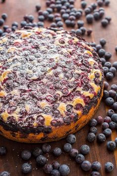 a blueberry cheesecake on a wooden table surrounded by blueberries