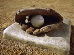 a baseball mitt with a ball in it sitting on top of a stone slab