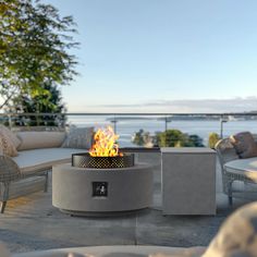 a fire pit sitting on top of a cement patio next to a body of water