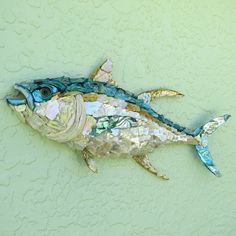 a fish made out of scrapbook paper on a green wall with blue and gold accents