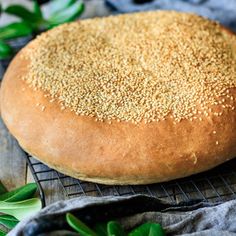 a loaf of bread sitting on top of a cooling rack next to some green leaves