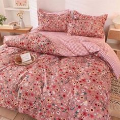 a bed with pink flowers on it in a room next to a table and lamp