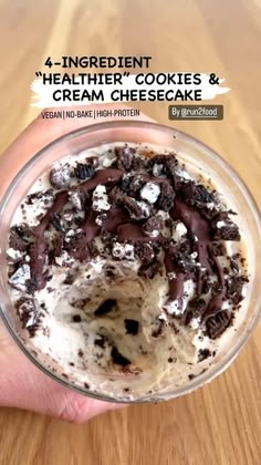 a hand holding a glass bowl filled with ice cream and chocolate chips on top of it