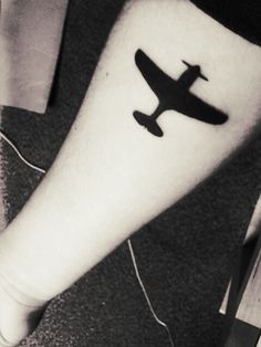 a black and white photo of a person's foot with an airplane tattoo on it