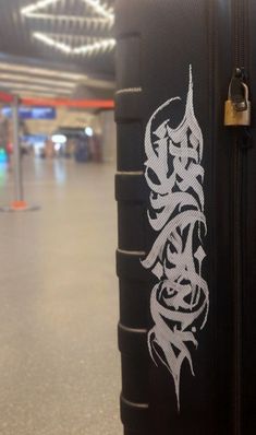 a piece of luggage with graffiti on it in an airport or terminal area, showing the handles and handlebars