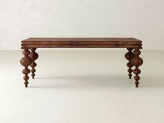 a wooden table with three legs and an intricately carved design on the top, against a white background