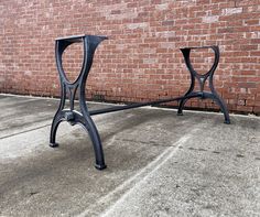 a metal table sitting on top of a sidewalk next to a brick wall