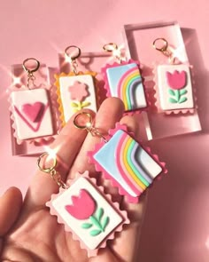 a person is holding several small key chains in their hand and there are four different designs on them