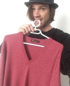 a man is holding up a pink shirt to his mouth while he brushes his teeth