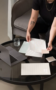 a person sitting at a table with a laptop and papers in front of them on it