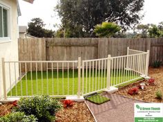 a fenced in backyard with grass and flowers