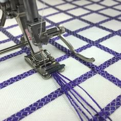 a close up of a sewing machine with purple thread on the table cloth behind it