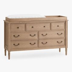 a dresser with drawers and white pillows on top