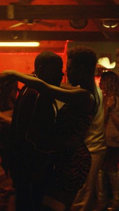 two people hugging each other in front of a group of people at a dance party