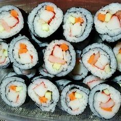 there are many sushi rolls in the plastic container with carrots and cheese on them