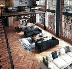 a living room filled with lots of furniture next to tall windows on top of a wooden floor