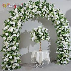 white flowers and greenery are arranged around a table with a small tree on it