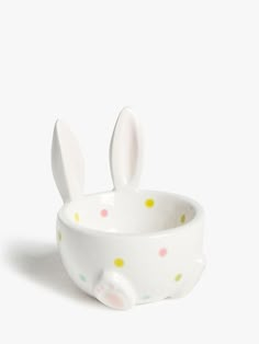 a white bowl with polka dots and bunny ears in the shape of an egg cup