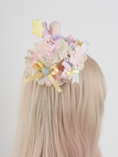 a woman with blonde hair wearing a pink and yellow flowered headpiece on top of her head