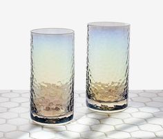 two glasses sitting on top of a white tiled floor