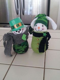 two stuffed snowmen wearing green hats and sweaters