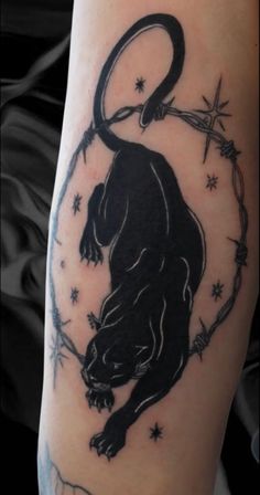 a black panther tattoo on the arm with barbed wire around it and stars in the background