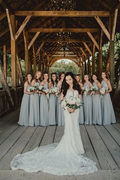 a bride and her bridal party standing in front of a wooden structure with chandelier