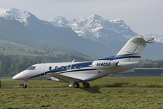 an airplane is parked on the runway with mountains in the background