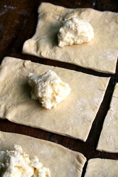 four uncooked pita breads with cheese on them sitting on a wooden table