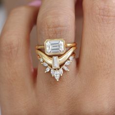 a close up of a person's hand wearing a ring with an emerald and diamond