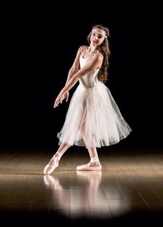 a young ballerina is posing for the camera