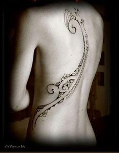 the back of a woman's body with an intricate tattoo on her left side